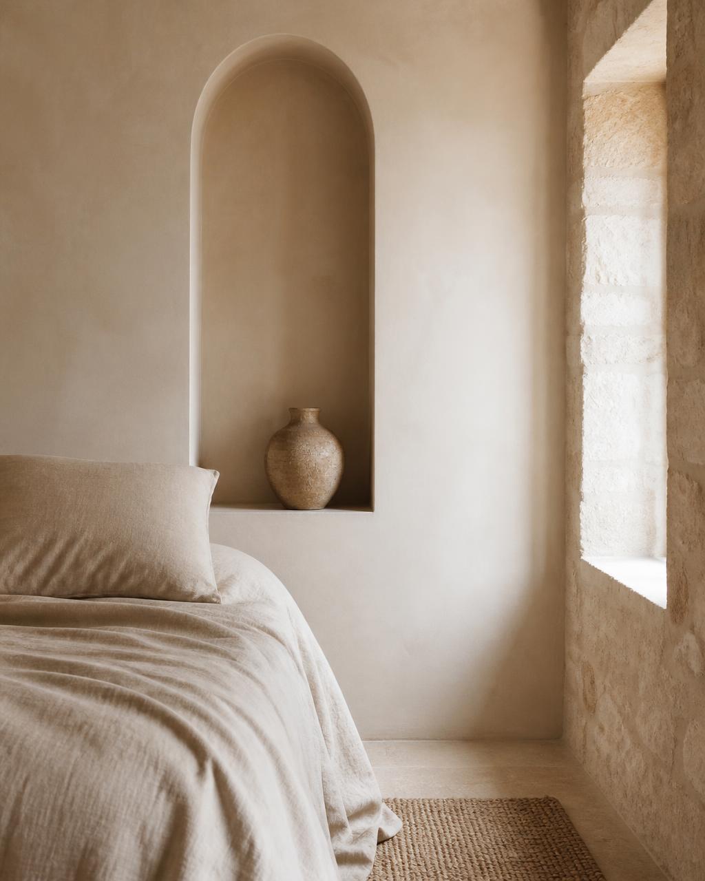 Interior minimalista en tonos arena con nicho en arco y ropa de cama en lino, interiorismo cálido DreamHome
